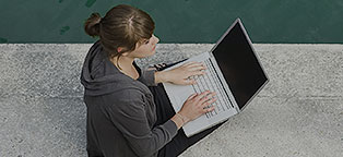 Woman outside typing on laptop 