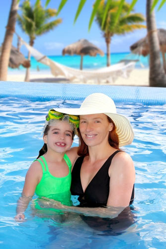 Mother and daughter in pool with palm trees in background