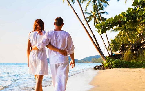 two honeymooners walking along the beach