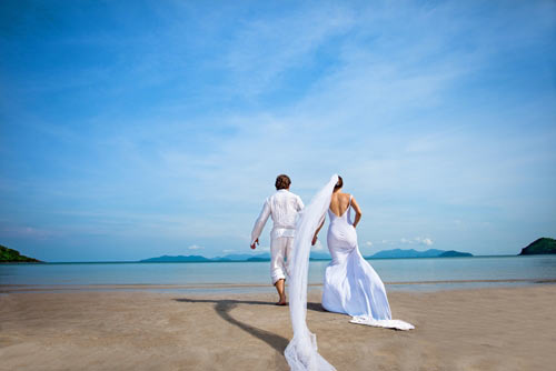 two newlyweds walking along the beach