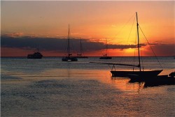 sail boats anchored in bay at sunset